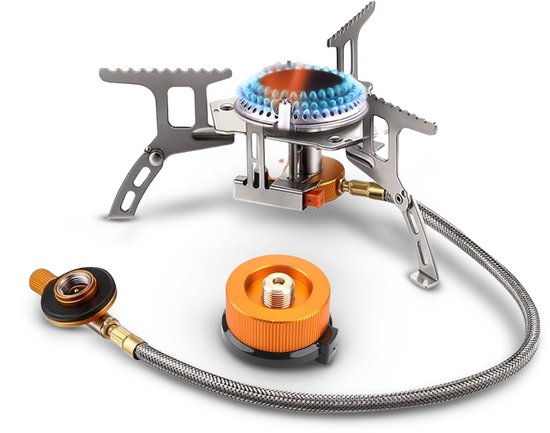 Réchaud de camping argenté avec des accents orange, connecté à une bouteille de gaz par un tuyau flexible.