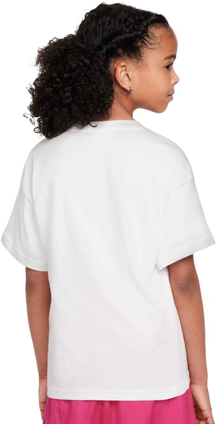 Meisje met krullend zwart haar in een paardenstaart, van de zijkant gezien, in een wit T-shirt met korte mouwen en een zwart Nike logo.