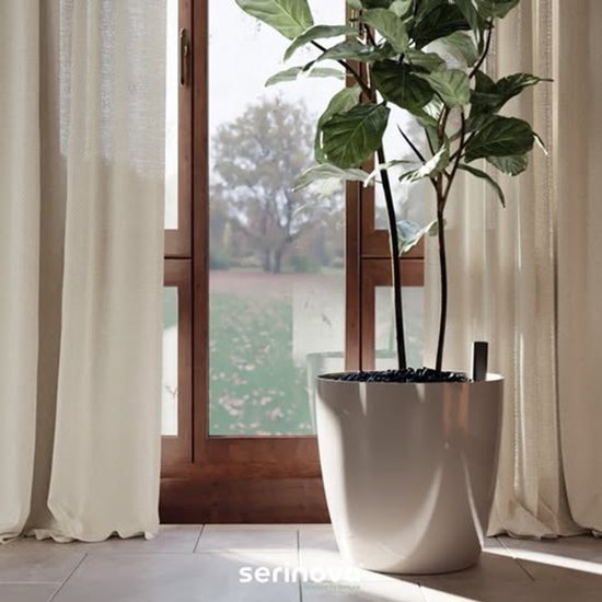 Grand pot de fleurs blanc Serinova avec une plante dans un salon près d'une fenêtre.