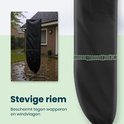 Zwarte parasolhoes met stevige riem en gesp. Bevestigd aan een parasolvoet, nat van de regen.