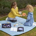Twee meisjes spelen op een kleed in de tuin met de zonnestelsel schijven en poster.