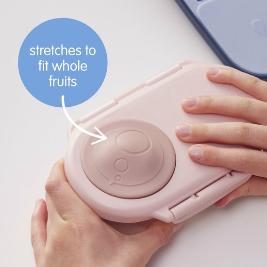 Mains d'enfant fermant une boîte à goûter b.box rose pâle, qui "s'étire pour contenir des fruits entiers".