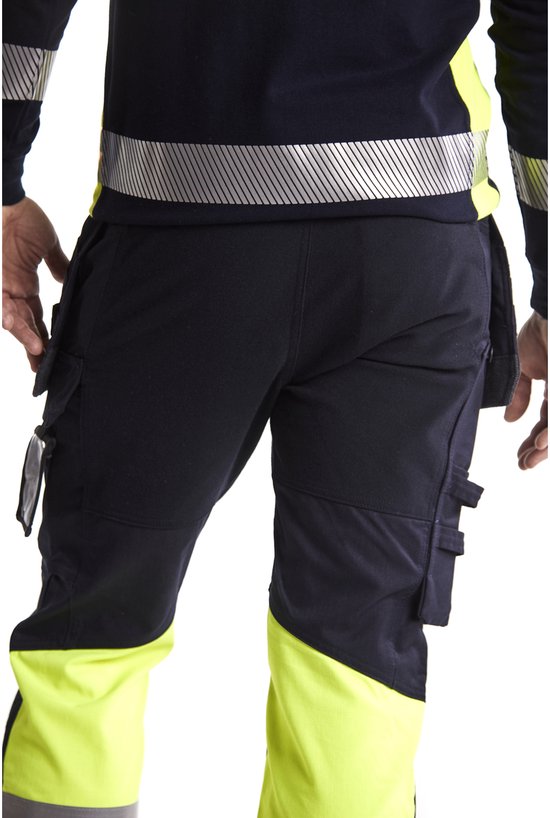Achterkant van een donkerblauwe werkbroek met gele en grijze reflecterende banden.