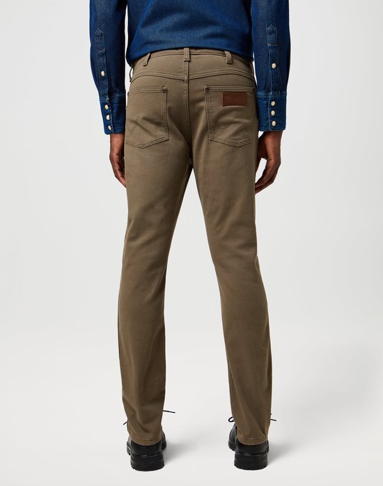 Achterkant man in olijfgroene Wrangler broek en spijkerblouse, zwarte schoenen.