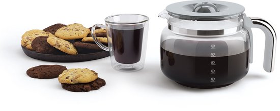 Glazen koffiekan met grijze deksel en handvat, naast een glas koffie en koekjes.