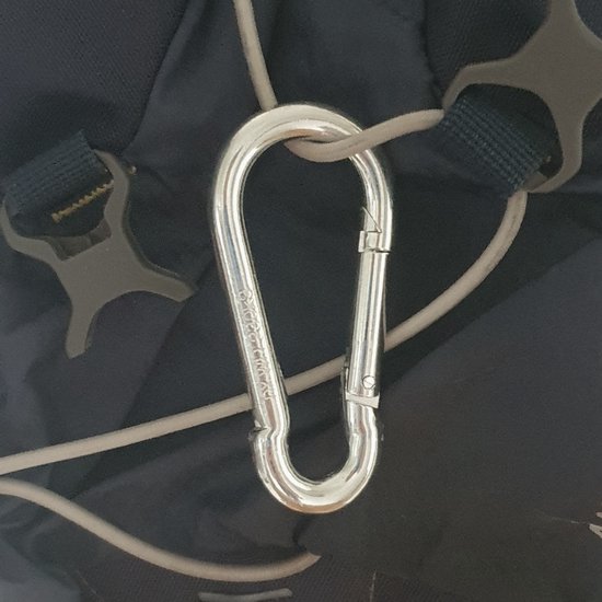 Gedetailleerde opname van een zilveren karabijnhaak aan een donkerblauwe rugzak.