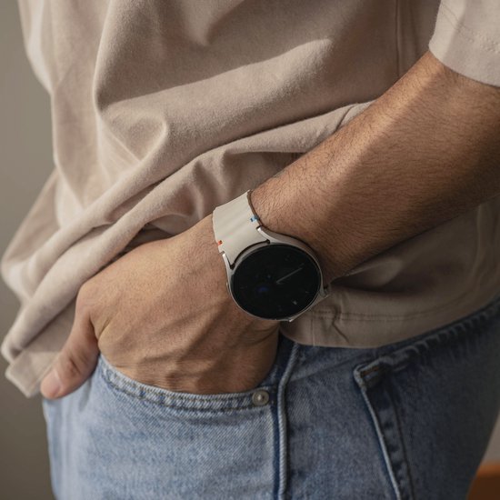 Mannelijk pols met een smartwatch en een crèmekleurig siliconen horlogebandje met golvend patroon.