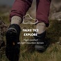 Pieds en chaussettes de randonnée Falke beiges et chaussures de randonnée marron, marchant sur l'herbe.