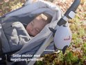 Slapende baby in een grijze kinderwagen met een witte rakketvormige Rockit babyrocker, 'Stille motor met regelbare snelheid'.