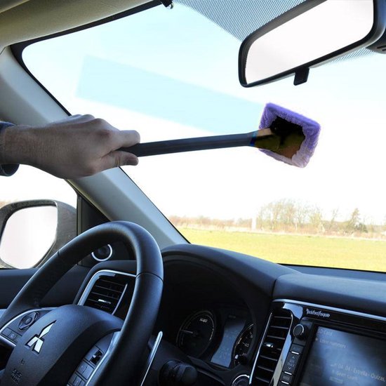 Hand gebruikt grijze steel met paarse microvezelkop om autowindscherm schoon te maken.