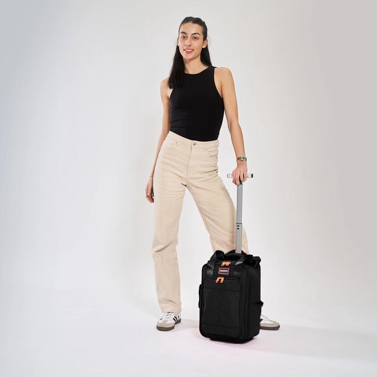 Vrouw met zwarte Cabin Max trolleytas met oranje accenten en wieltjes.