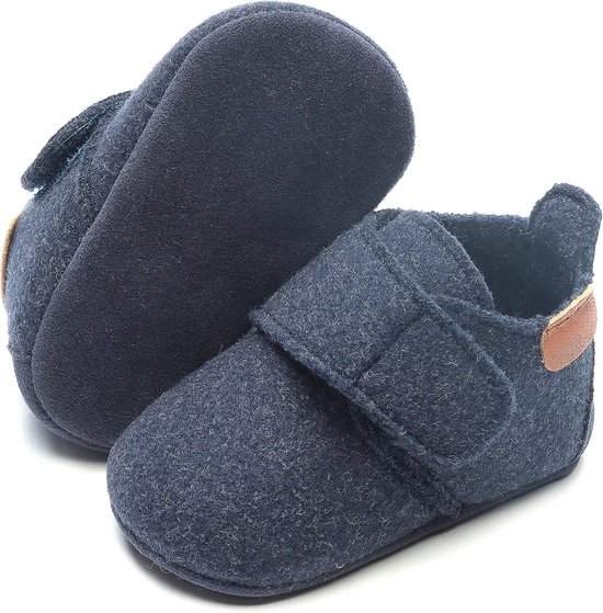 Onderkant en zijkant van een donkerblauwe babyslof met klittenbandsluiting en bruine hielaccent.