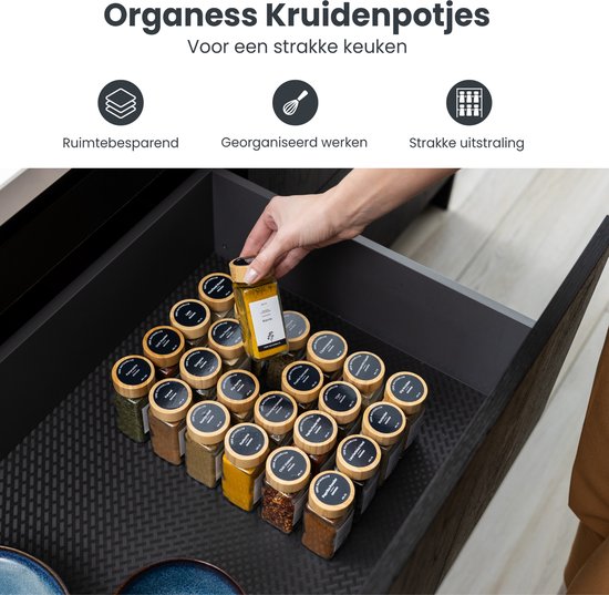 Kruidenpotjes met bamboe deksels georganiseerd in een keukenla. Textuur van de la mat is zichtbaar.