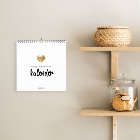 Verjaardagskalender met gouden hart en tekst 'kalender' hangend aan een muur in een interieur.