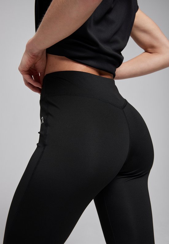 Detail van een zwarte sportlegging met V-vormige naad op de billen en een klein logo op de heup.