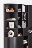 Zwarte open vakkenkast met ronde hoek, gevuld met boeken en decoratieve objecten.