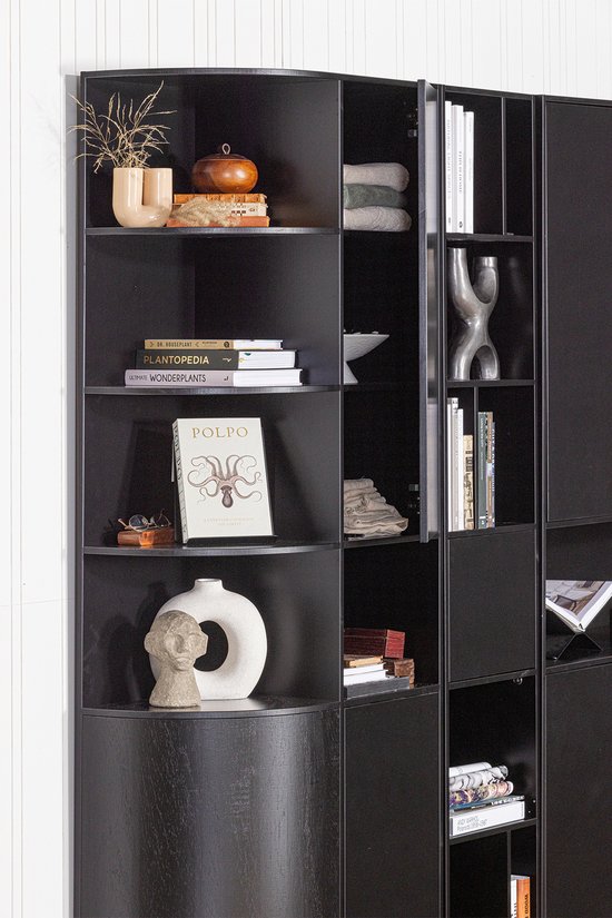 Zwarte open vakkenkast met ronde hoek, gevuld met boeken en decoratieve objecten.