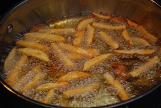 Frietjes bakken in een pan met bruisende hete olie.