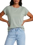 Model met lichtgroene effen top met opgerolde mouwen en jeans.