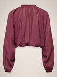 Achterkant van een bordeauxrode crop top met rucheskraag, strikdetail en ballonmouwen.