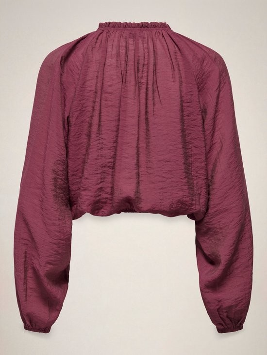 Achterkant van een bordeauxrode crop top met rucheskraag, strikdetail en ballonmouwen.