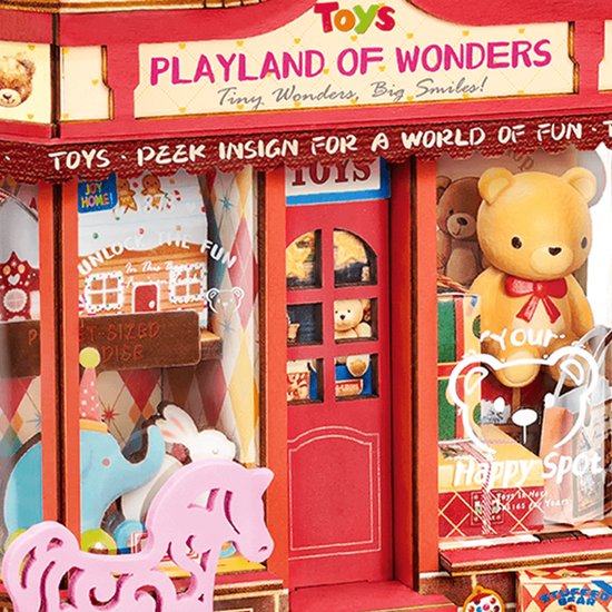 Gedetailleerde miniatuur speelgoedwinkel 'Playland of Wonders' met rode deur, teddybeer en speelgoed.