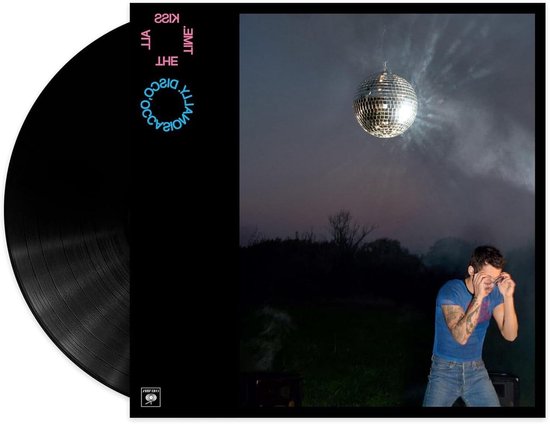 Zwarte vinylplaat met 'Kiss The Disco' artwork. Rechts, een man in blauw shirt en jeans onder een discobal in een rokerige buitenlucht.