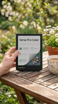Hand die de groene PocketBook Verse Pro Color vasthoudt aan een houten tafel in de tuin.