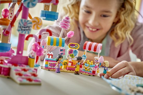 Kinderen bouwen samen aan het LEGO Friends Candy & Cupcake Reuzenrad met kermisattracties.