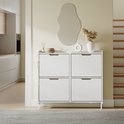 Witte schoenenkast met 4 lades, decoratie en een spiegel aan de muur erboven.