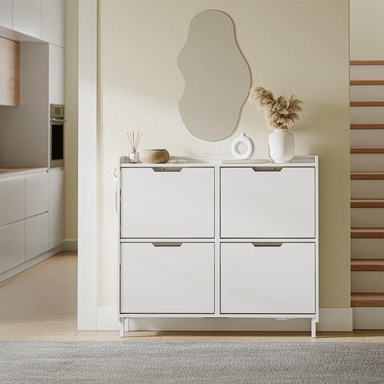 Witte schoenenkast met 4 lades, decoratie en een spiegel aan de muur erboven.