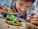 Een jongen speelt enthousiast met de groene en gouden LEGO Ninjago racewagen (71828) en een rode minifiguur.