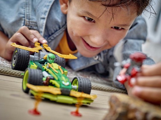 Een jongen speelt enthousiast met de groene en gouden LEGO Ninjago racewagen (71828) en een rode minifiguur.