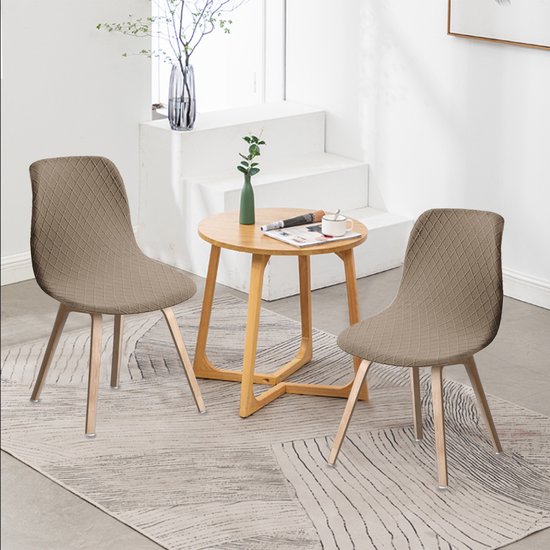 Twee beige stoelhoezen met ruitpatroon in een woonkamer opgesteld met bijzettafel.