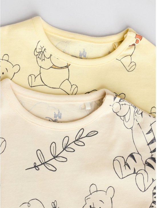 Sluiting van twee rompertjes. De voorste is crèmekleurig met Eeyore en Tigger, de achterste is geel met Winnie de Poeh.