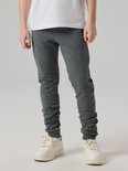 Grijze joggingbroek met kreukels aan de onderkant, gedragen door een jongen.