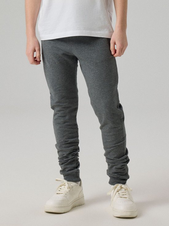 Grijze joggingbroek met kreukels aan de onderkant, gedragen door een jongen.