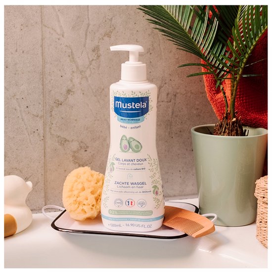 Mustela zachte wasgel met avocado, met pompdispenser, naast een spons en kam.