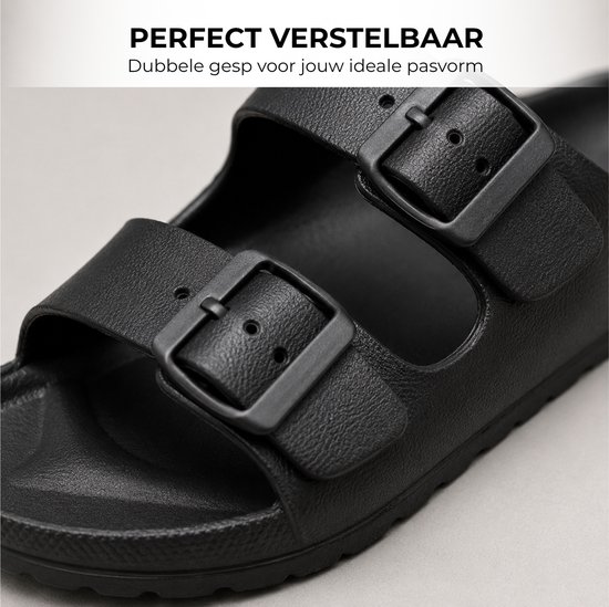 Close-up van een zwarte slipper met dubbele gespen.
