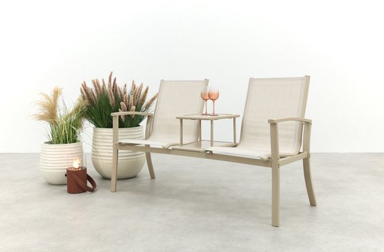 Beige aluminium tuinbank met stoffen zittingen en middenplateau, met planten en een lantaarn ernaast.