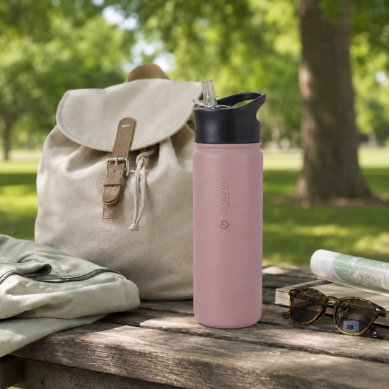Roze 500ml drinkfles met zwarte rietjesdop, naast een rugzak op een picknicktafel.