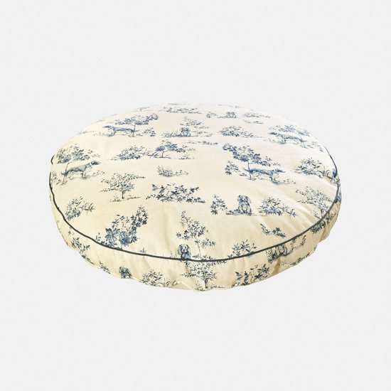 Ronde crème kleurige hondenmat met een blauwe patroon van honden en bomen.