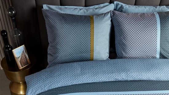 Blauw dekbedovertrek met geometrische patronen en een gouden bies, met bijpassende kussenslopen.