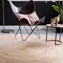 Een rond, natuurlijk jute vloerkleed met een leren vlinderstoel en bijzettafel.