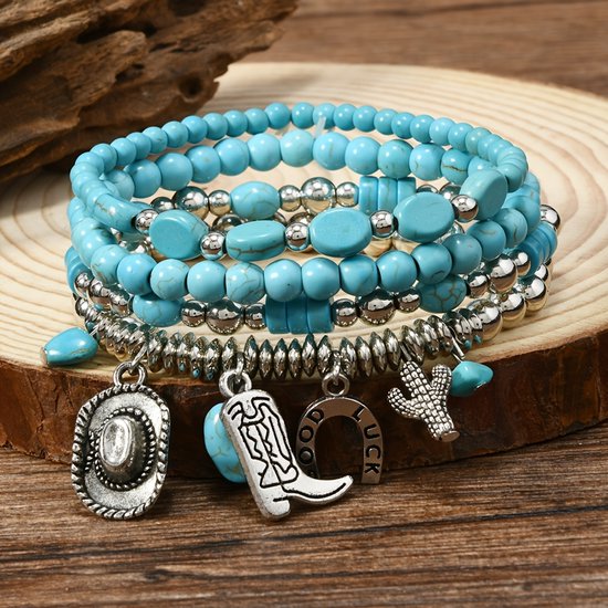 Ensemble de bracelets turquoise et argent avec des breloques chapeau de cowboy, botte et fer à cheval, sur fond de bois.