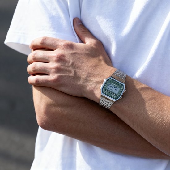 Zilverkleurig Casio horloge met groen display gedragen om de pols van een man.