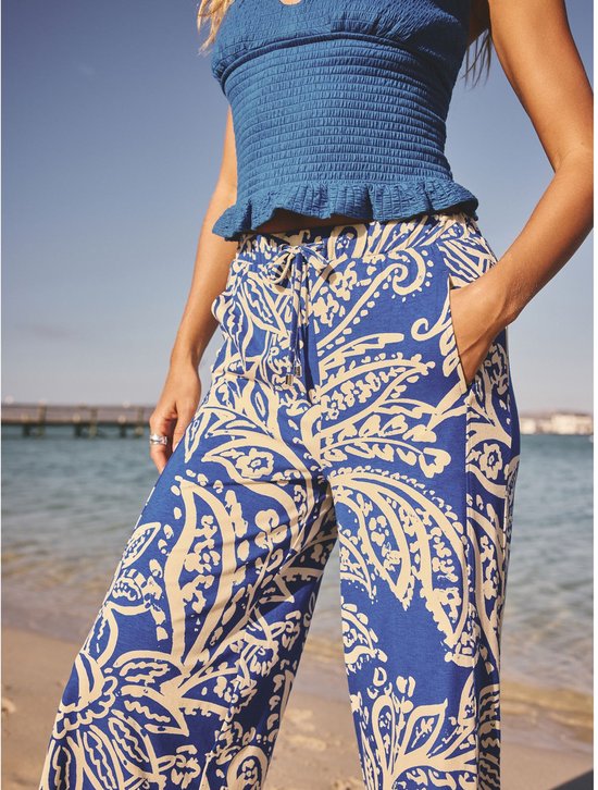 Model draagt een blauwe crop top en een culotte met blauwe en crème paisley print.