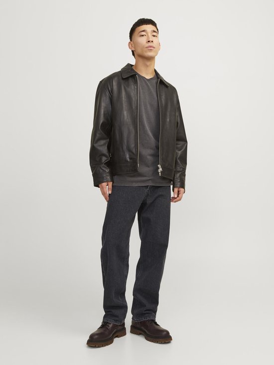 Model draagt losse, zwarte jeans met leren jack.