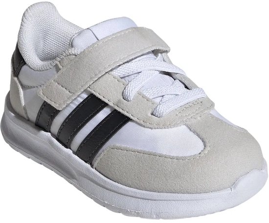 Witte kindersneaker met grijze suède overlays, zwarte Adidas-strepen en klittenbandsluiting.