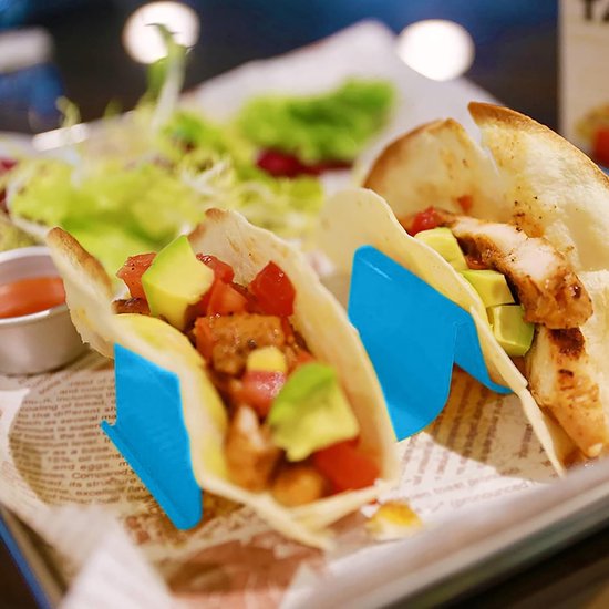 Twee blauwe tacohouders met gevulde taco's en een salade.
